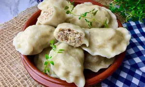 Pyszne pierogi z kaszą gryczaną i twarogiem, udekorowane gałązkami ziół, kuszą swoim domowym wyglądem.