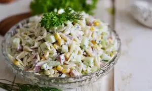 Pyszna sałatka z makaronem orzo, ogórkiem, kukurydzą i szynką, udekorowana natką pietruszki i koperkiem.