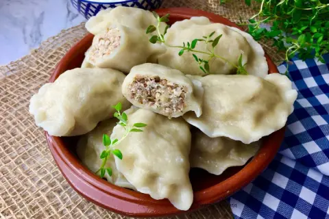 Pyszne pierogi z kaszą gryczaną i twarogiem, udekorowane gałązkami ziół, kuszą swoim domowym wyglądem.