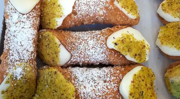 Chrupiące rurki z kremem, posypane cukrem pudrem i pistacjami, kuszą swoim wyglądem.