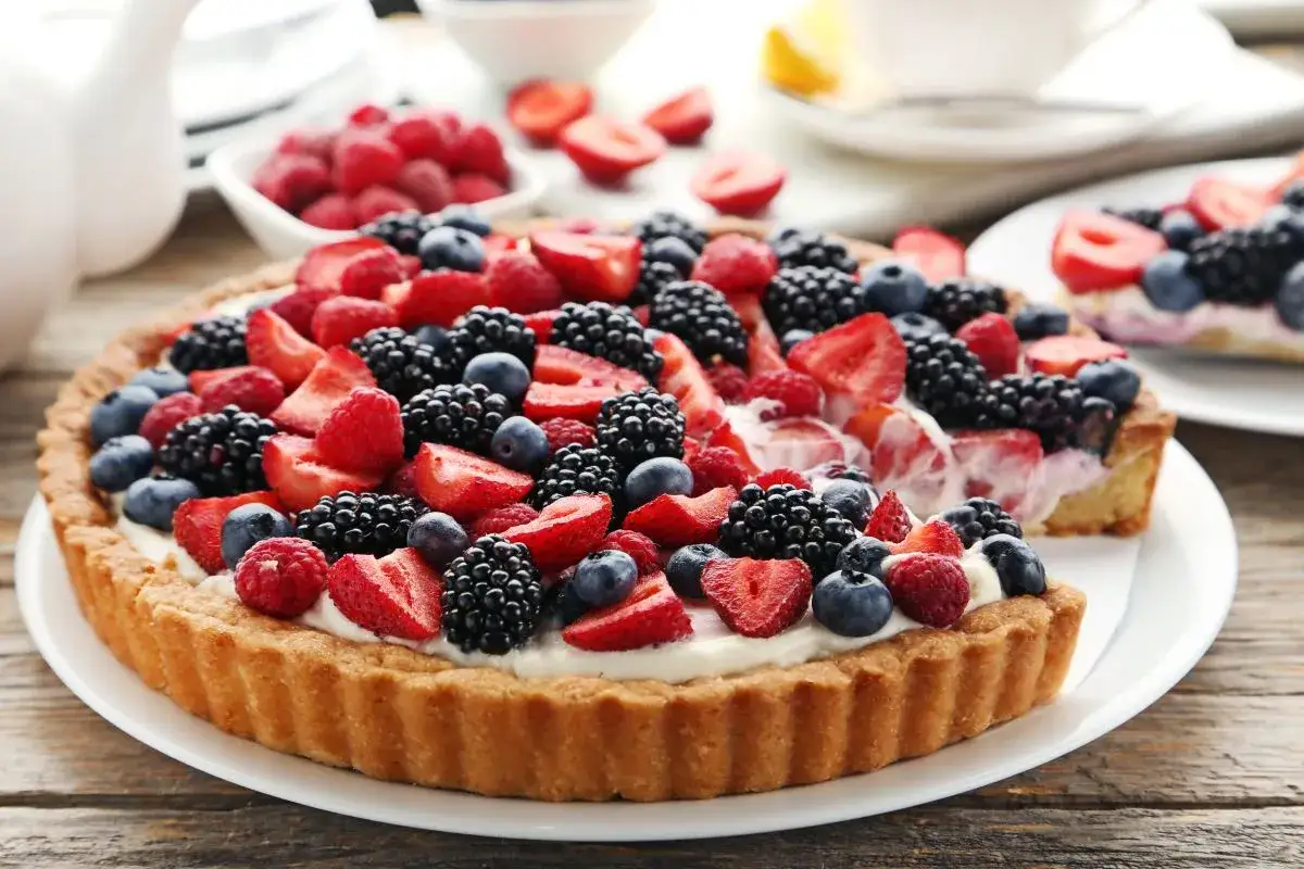 Pyszna tarta na słodko, obficie udekorowana świeżymi malinami, bor&oacute;wkami, jeżynami i truskawkami. Idealna na deser.