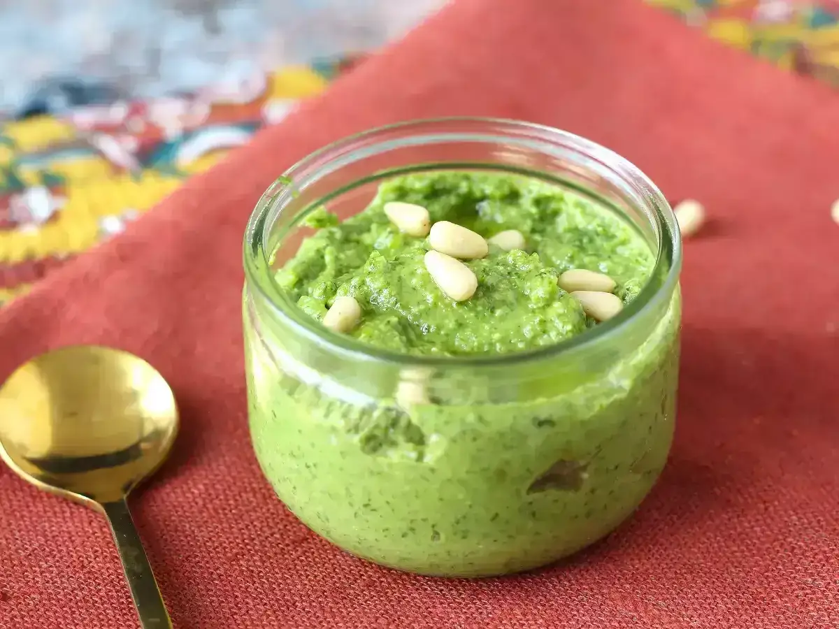 Słoiczek domowego pesto z rukoli, ozdobiony orzeszkami pinii. Idealne do makaronu i kanapek.