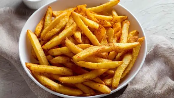 Chrupiące frytki z airfryer, posypane przyprawami, w białej misce. Idealna przekąska na szybki obiad.